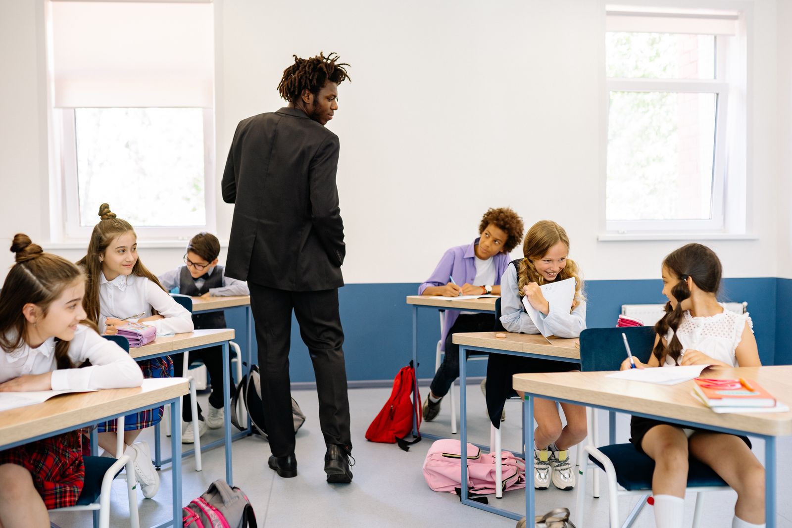 Teacher walking between pupils' desks in a secondary school classroom