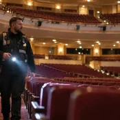 Venue security officer patrolling an empty theatre auditorium with a torch
